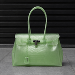 Sac Jelly Firkin Croco Jade vert amande effet croco posé au sol, vue studio devant un rideau métallique noir