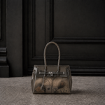 Mini sac Jelly Firkin coloris Onyx noir rempli d'objets, posé devant une porte sombre
