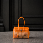 Mini sac Jelly Firkin coloris Sunset orange coucher de soleil rempli d'objets, posé devant une porte sombre, vue alternative
